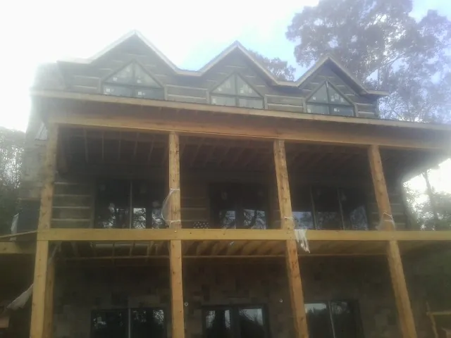 Dormers and porch framing on a large log home under construction — Roof Coating work by our crew in Crescent